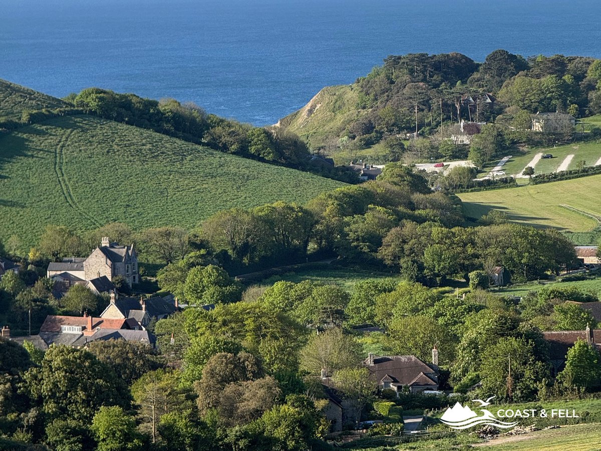 West Lulworth village from the return path — rolling fields, golden light and sea beyond