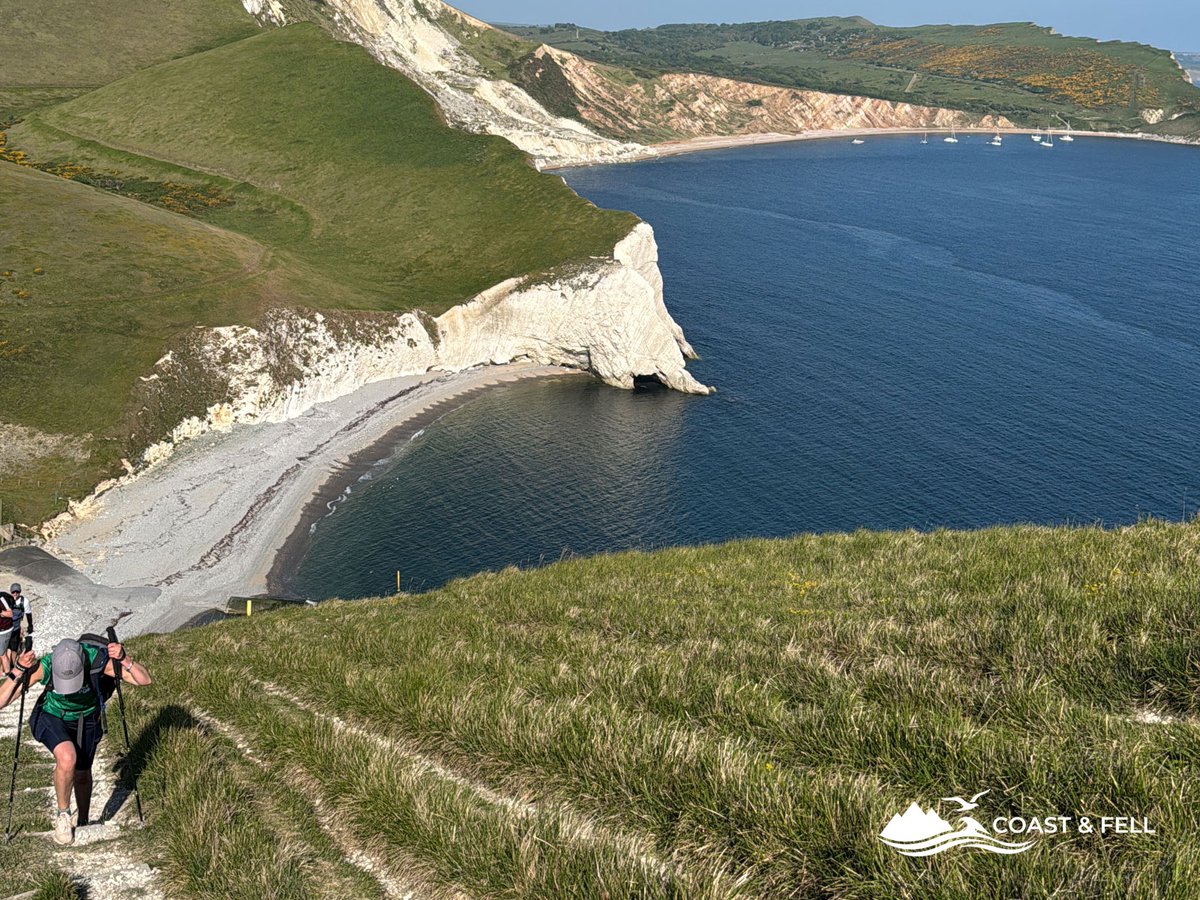 Participants on stone steps with stunning bay and chalk cliffs and sailboats below