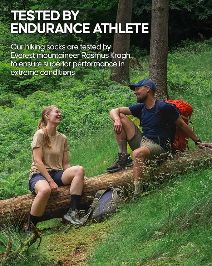 Two hikers resting on a fallen log in woodland, wearing Danish Endurance hiking socks