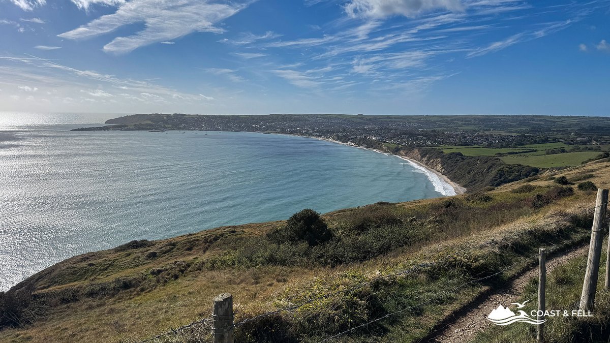 Swanage bay from the Ballard Down ridge path, with the town curving around the water and the fence line leading along the down