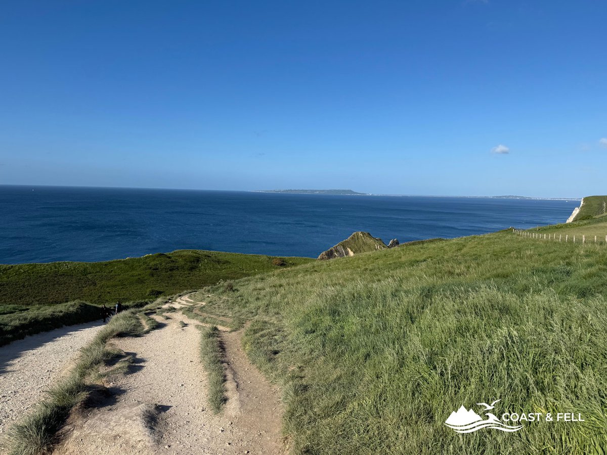South West Coast Path heading west toward Bat's Head under blue sky, Dorset