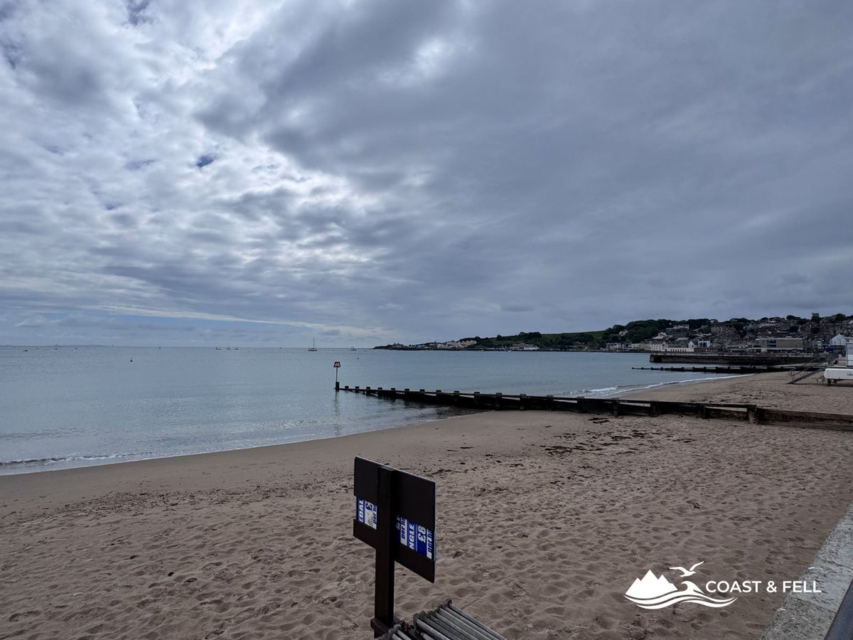 Swanage beach from promenade grey overcast sky empty sand with harbour and pier visible in background