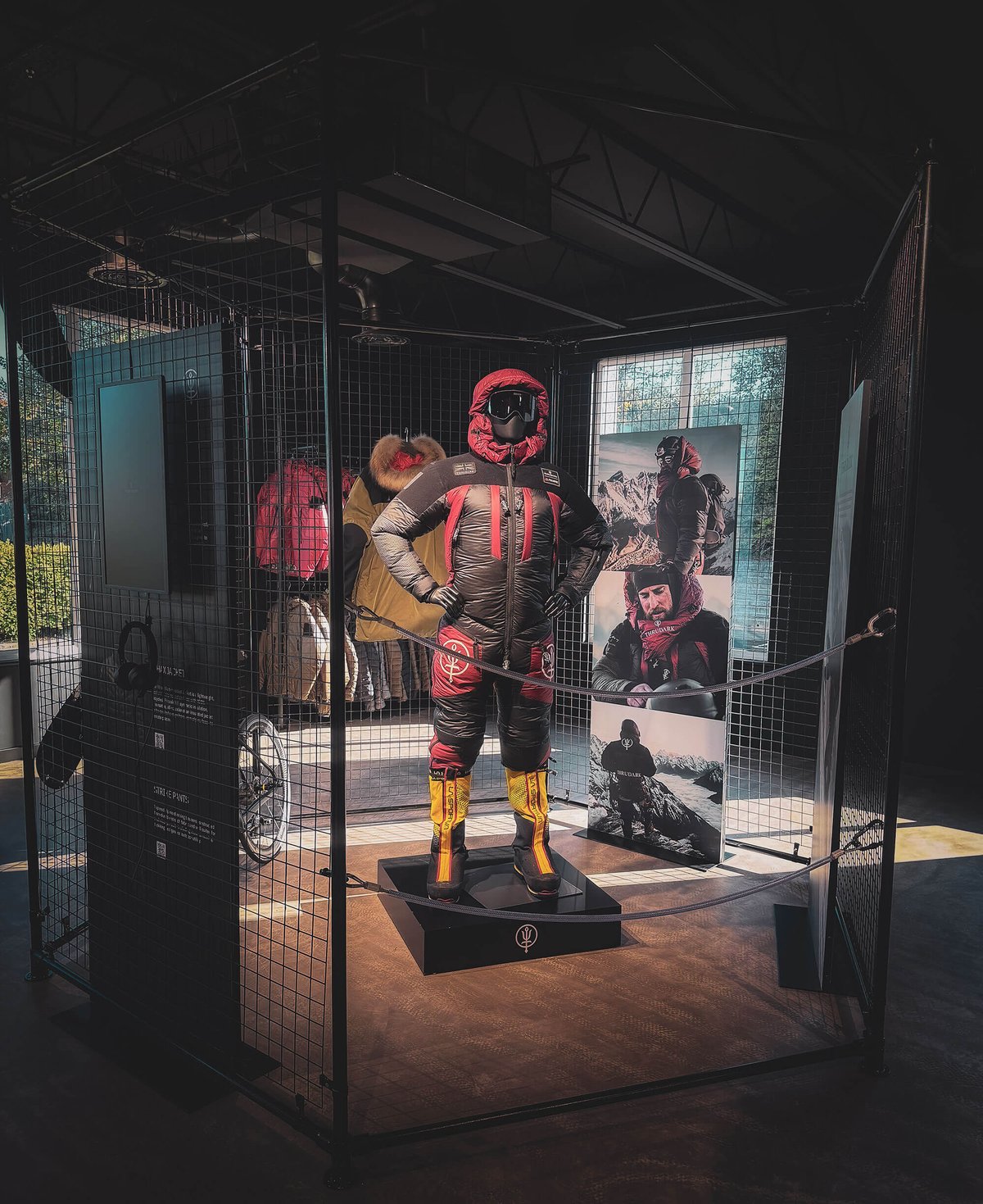 A kit display inside ThruDark's Sentinel House store in Poole, a mannequin in a caged enclosure, backed by the brand's mountain expedition photography