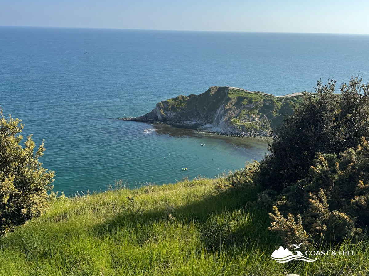 Rocky headland and turquoise cove from coast path above Lulworth during Jurassic Coast Challenge