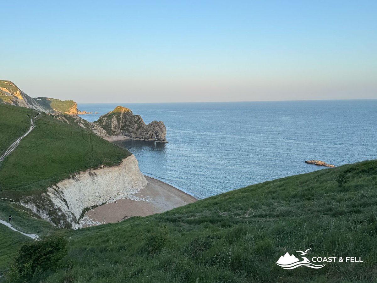 Durdle Door limestone arch from above in evening light beach below