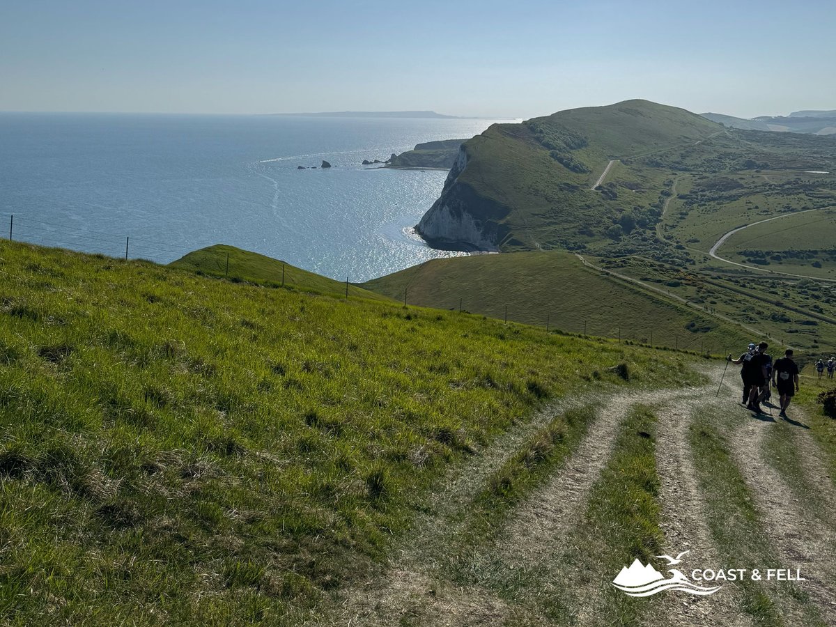 Participants descending coast path with White Nothe chalk cliffs and sea in the distance