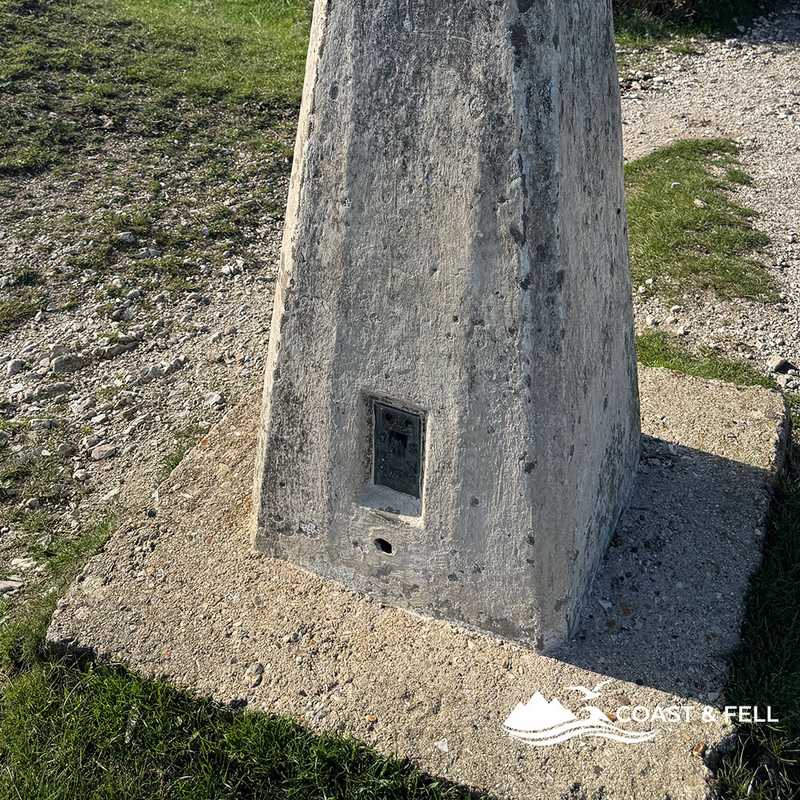 The trig pillar on Ballard Down up close, with the ridge path behind