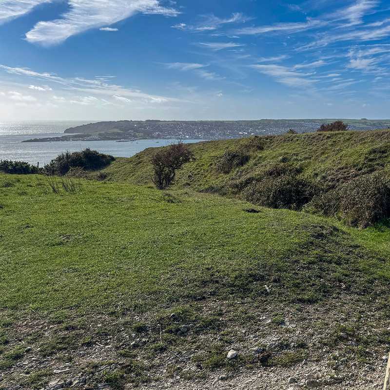 The trig pillar on Ballard Down with the ridge path running on towards Swanage, Dorset