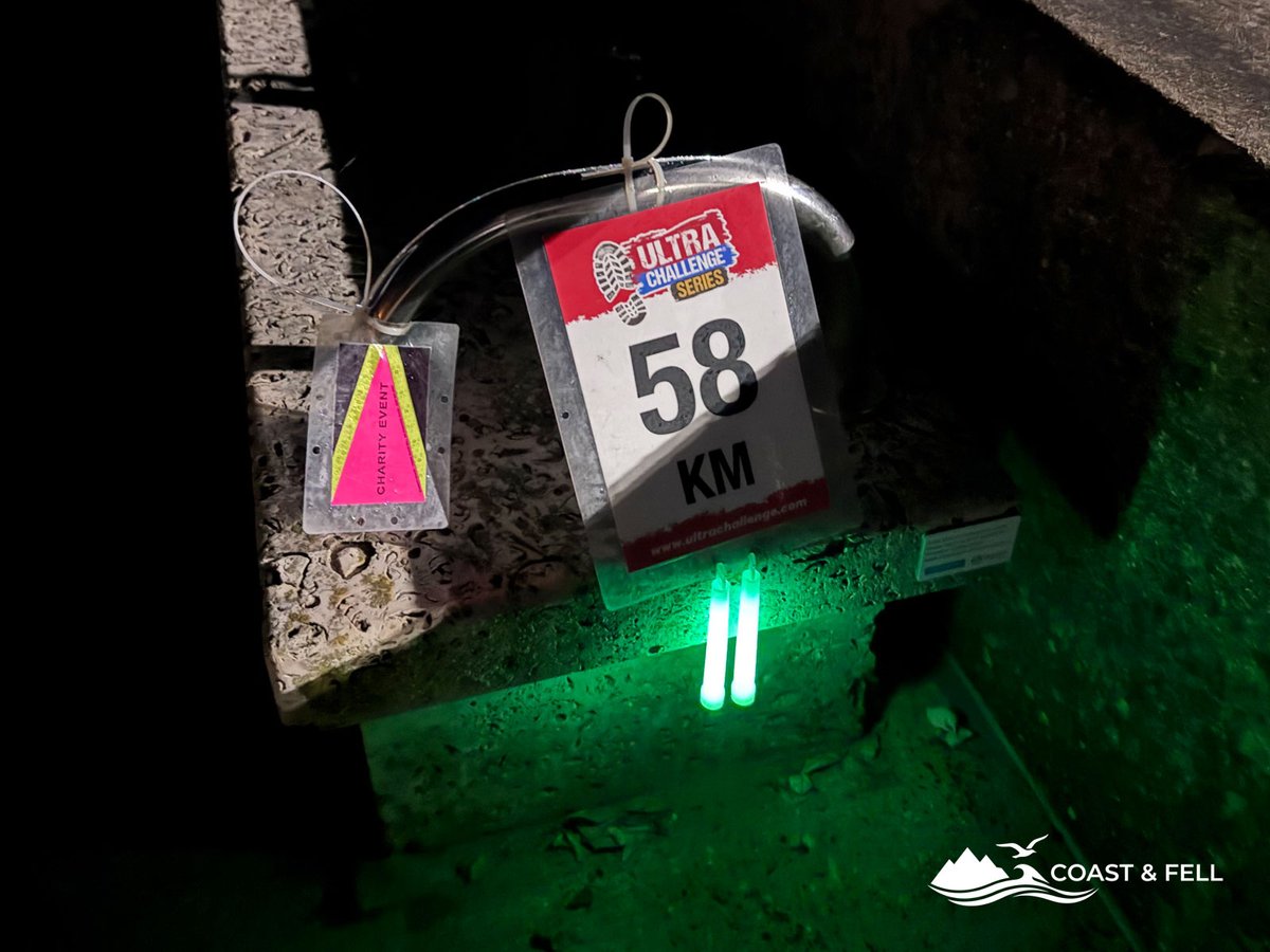 Ultra Challenge Series 58km marker sign at night illuminated by green glow sticks on Weymouth promenade