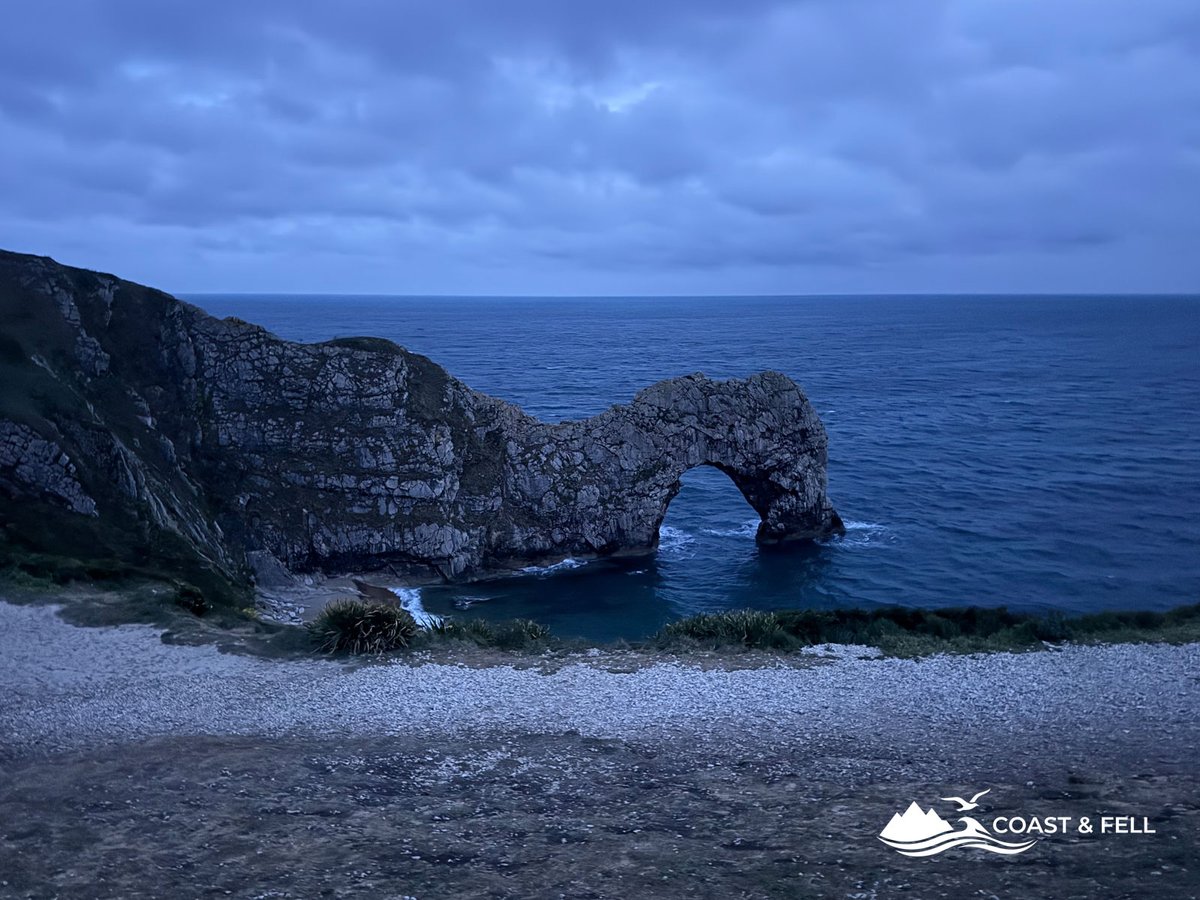Durdle Door limestone arch at night in deep blue dark light with sea below and no other people visible