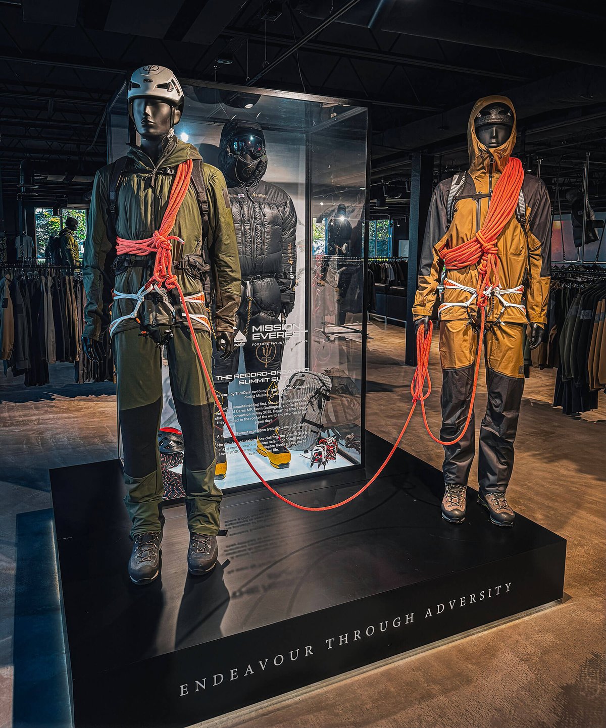 ThruDark's Mission Everest summit suit in a glass case at Sentinel House, flanked by two roped climbing mannequins, with the Endeavour Through Adversity motto on the plinth