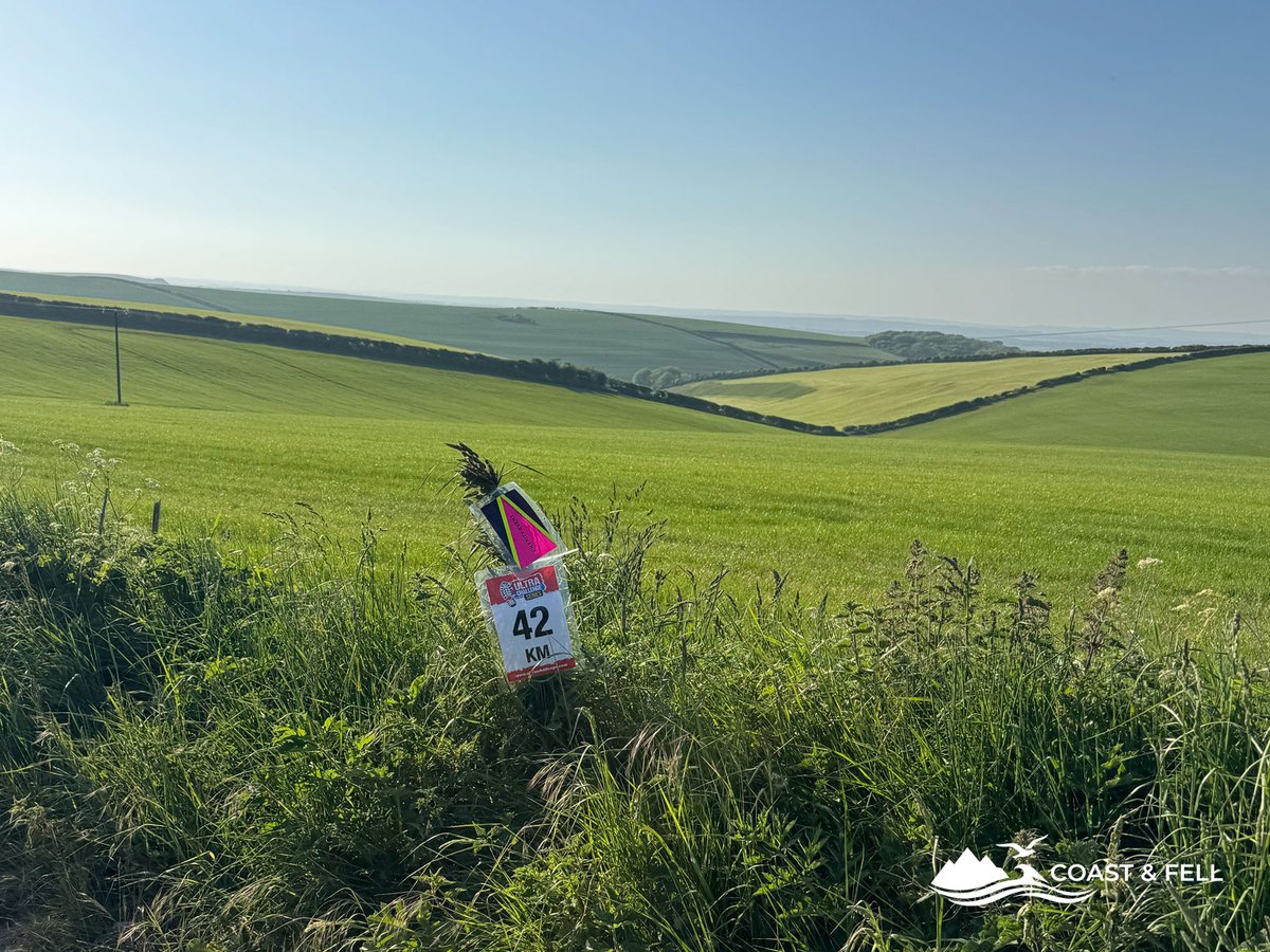 42km distance marker post on Jurassic Coast Challenge route with rolling green fields