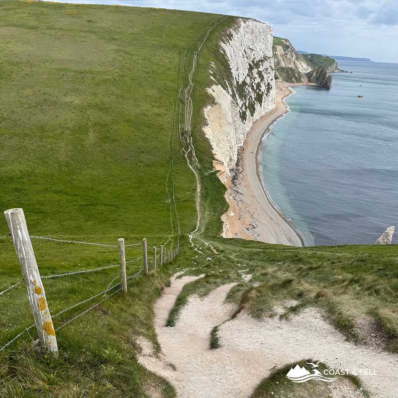 Coast path descending steeply toward Man o' War Bay with chalk cliffs